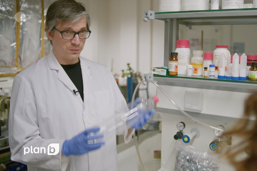 Dr. Christian Sonnendecker im Interview in einem Labor mit einer PET-Flasche in der Hand